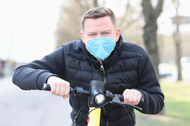 Hombre con máscara protectora médica paseos en scooter eléctrico por la ciudad