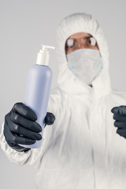 Un hombre con una máscara protectora médica sosteniendo un desinfectante para manos