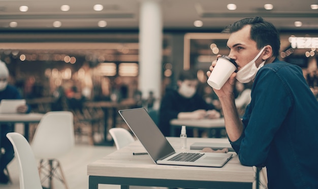 Hombre con una máscara protectora sentado en una mesa en un café. foto con espacio de copia