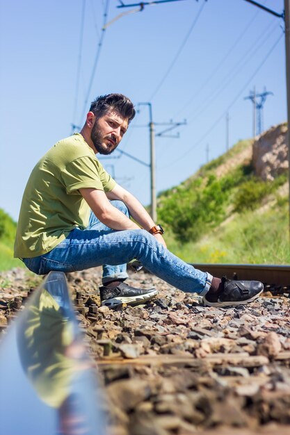 hombre con máscara protectora en las vías del ferrocarril tocando la guitarra