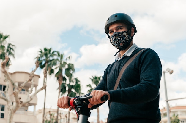 Hombre con máscara quirúrgica montando scooter para trabajar