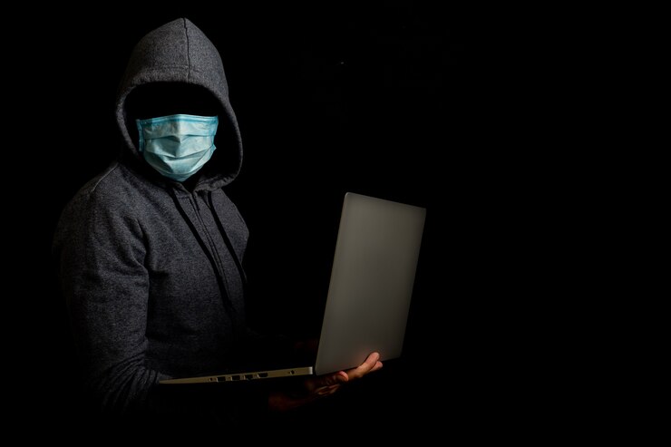 Foto el hombre con una máscara sin rostro y una capucha sostiene una computadora portátil en sus manos en un oscuro