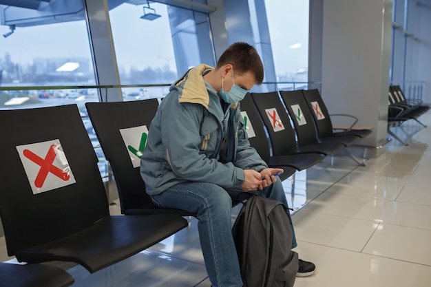 Foto hombre con máscara sentado en la sala de espera del aeropuerto