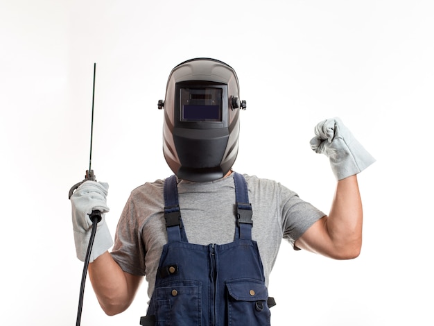 Un hombre con una máscara de soldadura, ropa y guantes robóticos, sosteniendo un cable con un electrodo de soldadura.