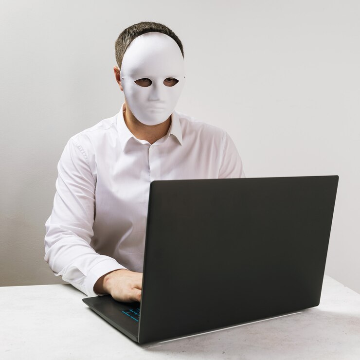 Foto un hombre con una máscara trabaja detrás de una computadora portátil el concepto de anonimato en internet