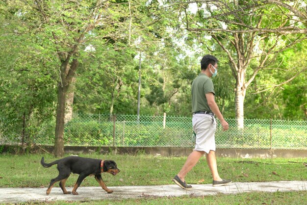 Hombre con mascarilla caminando con perro en el parque