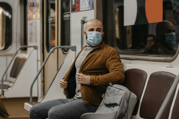 Un hombre con una mascarilla médica en la estación de metro.