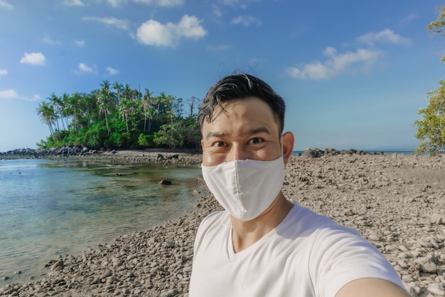 Hombre con mascarilla tiene un viaje al mar durante el verano en pandemia de covid