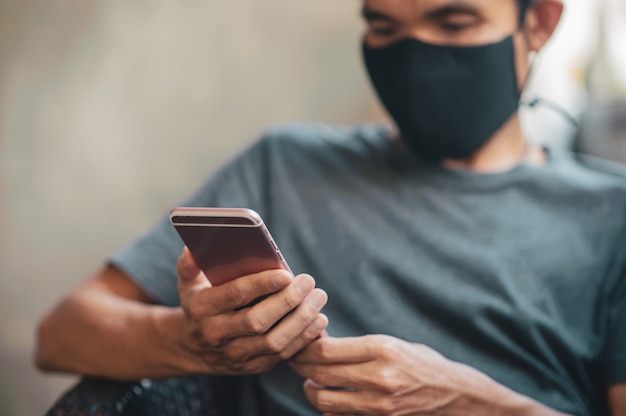 Hombre en una mascarilla usando un teléfono inteligente