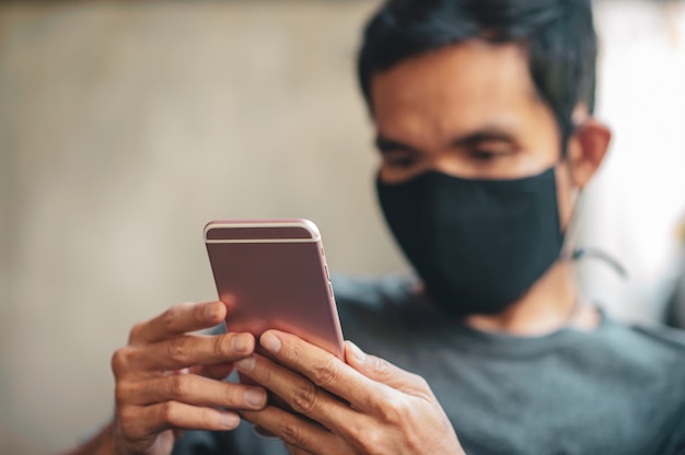 Hombre en una mascarilla usando un teléfono inteligente