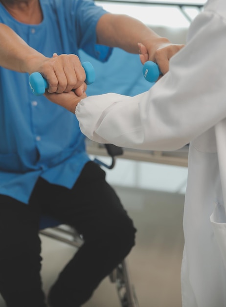 Hombre mayor asiático haciendo fisioterapeuta con el apoyo de una enfermera Anciano mayor sentado en un sofá en la sala de estar haciendo ejercicios con pesas para pacientes con cuidadores en cuidados de enfermería