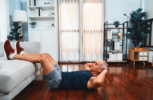Hombre mayor atlético y activo que usa muebles para apuntar eficazmente a los músculos con ejercicio en casa como concepto de estilo de vida saludable y en forma después de la jubilación