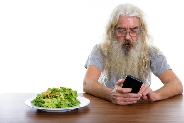 hombre mayor con barba que usa el teléfono móvil