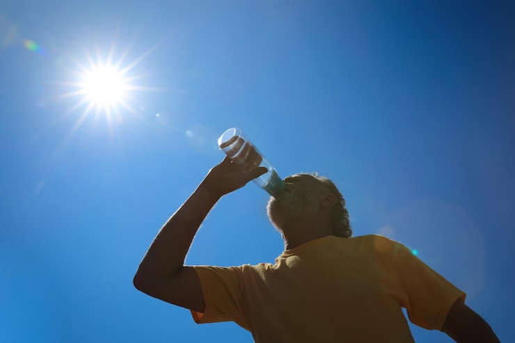 Foto hombre mayor bebiendo agua para prevenir un golpe de calor al aire libre vista de ángulo bajo