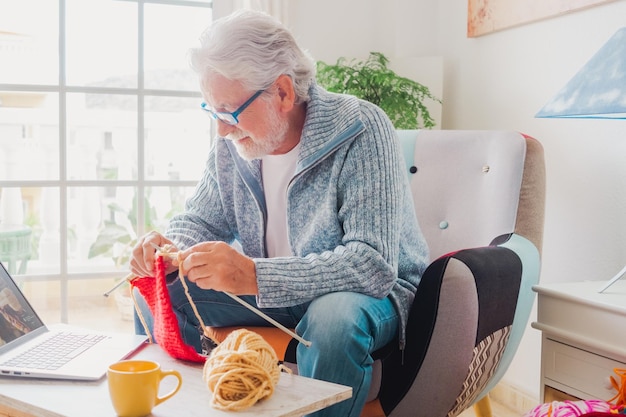 El hombre mayor en casa sigue el tutorial de punto en línea para relajarse y disfrutar de la actividad de ocio en casa descansando