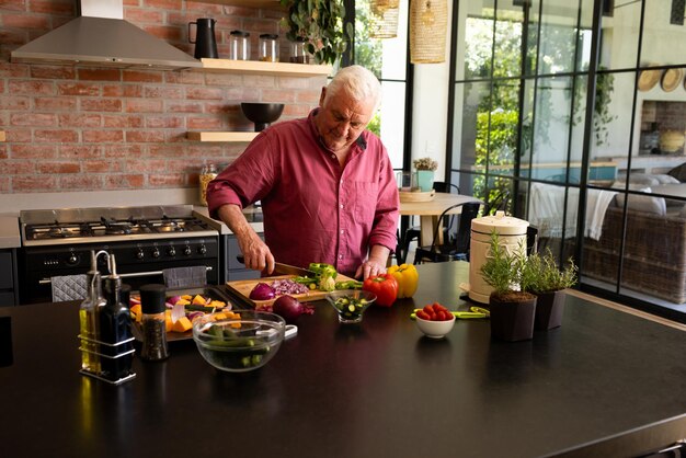 Hombre mayor caucásico enfocado preparando comida cortando verduras en el soleado espacio de copia de la cocina