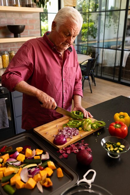 Foto hombre mayor caucásico feliz preparando comida cortando verduras en el mostrador de la cocina espacio de copia