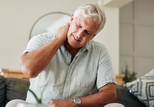 Hombre mayor con dolor de cuello y estrés sentado en casa con lesión en la columna masajeando músculos para osteoporosis y fibromialgia Mala salud cansado y anciano con artritis ortopédica y problemas de espalda