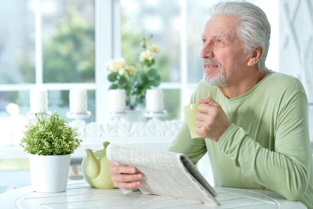 Hombre mayor emocional leyendo el periódico y posando en casa