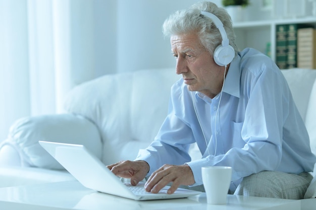 Hombre mayor emocional que usa la computadora portátil en casa