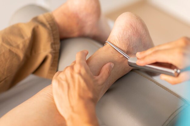 Un hombre mayor es tratado en una clínica de fisioterapia con un gancho y una técnica de fibrólisis diacutánea