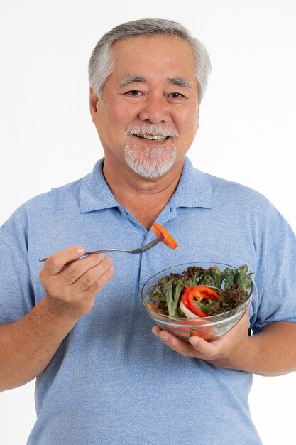 El hombre mayor de estilo de vida se siente feliz disfruta comiendo ensalada fresca de alimentos dietéticos aislado sobre fondo blanco.