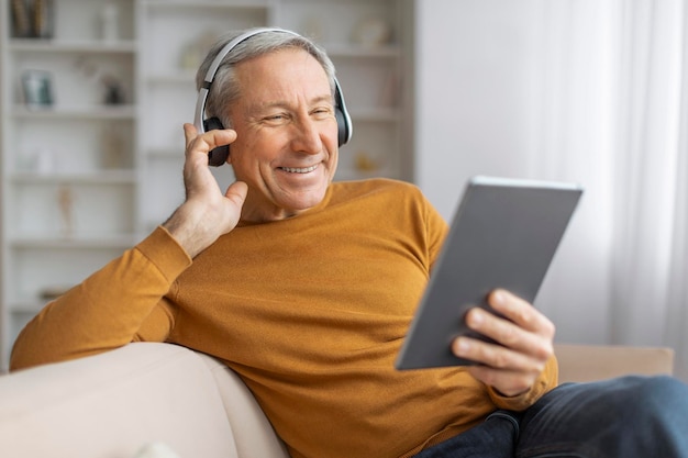 Hombre mayor feliz con auriculares usando una tableta