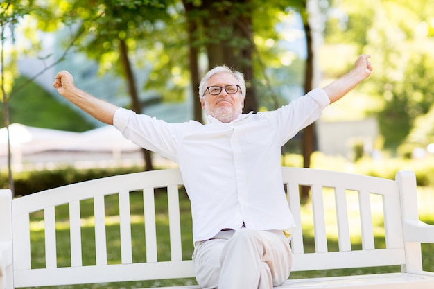 Foto hombre mayor feliz con gafas sentado en el parque de verano