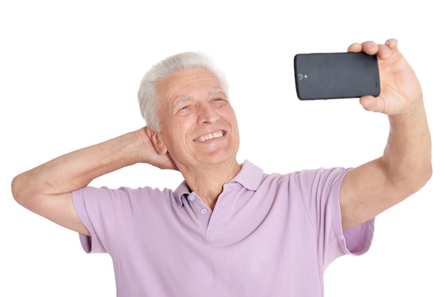 Hombre mayor feliz con smartphone tomando foto selfie sobre fondo blanco.