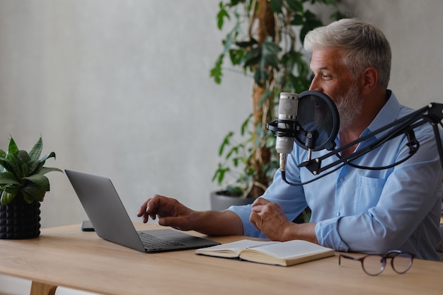 hombre mayor graba contenido de audio o conduce un programa de radio en un estudio de grabación un hombre con gris