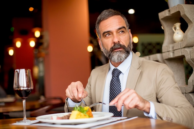 Hombre mayor guapo comiendo en el restaurante