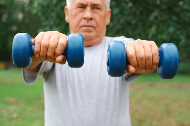 Hombre mayor haciendo ejercicio al aire libre Persona levantando pesas Anciano haciendo ejercicio en el parque Estilo de vida de personas sanas Entrenamiento deportivo activo Deportista anciano haciendo ejercicio físico Sesión de entrenamiento