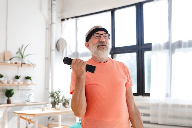 Foto hombre mayor haciendo ejercicios de fitness con clase virtual y sosteniendo pesas concepto de bienestar y bienestar