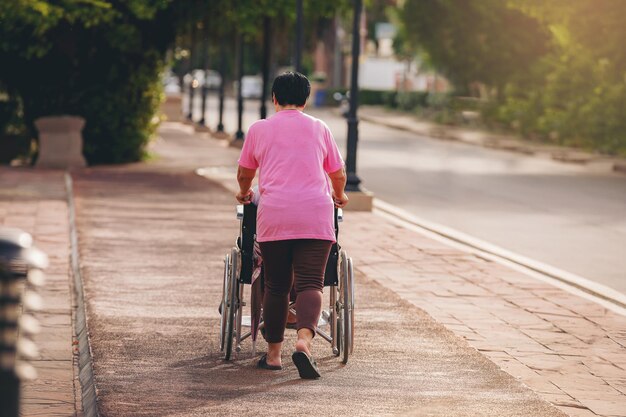 Hombre mayor maduro discapacitado en silla de ruedas relajándose en un parque por su esposa cuidar juntos
