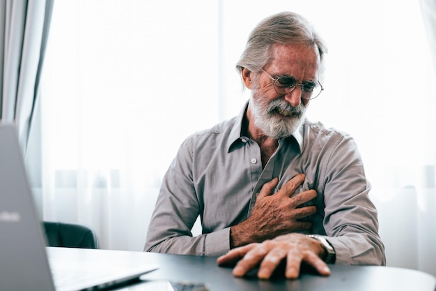 Foto hombre mayor con la mano en el pecho y sufriendo de problemas cardíacos en casa