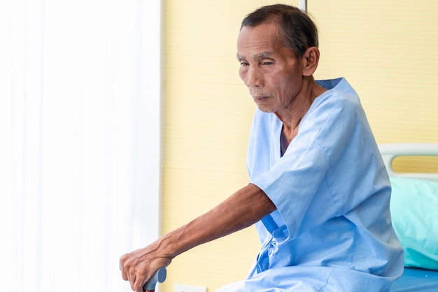 Hombre mayor paciente con bastón en la habitación del hospital.