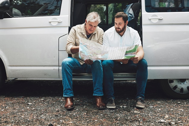 Hombre mayor padre e hijo con mapa en viaje de aventura buscando dirección de destino en furgoneta hablando y viajando juntos Amigos de la familia y hombres turistas junto con transporte en viaje por carretera