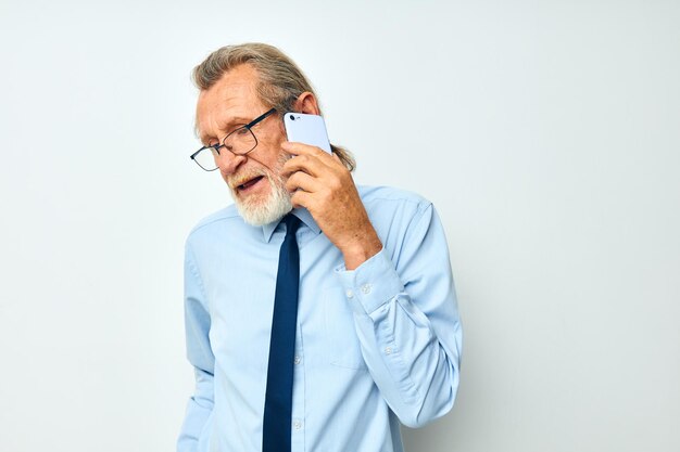 Hombre mayor de pelo gris con una camisa con corbata con una vista recortada de tecnología telefónica