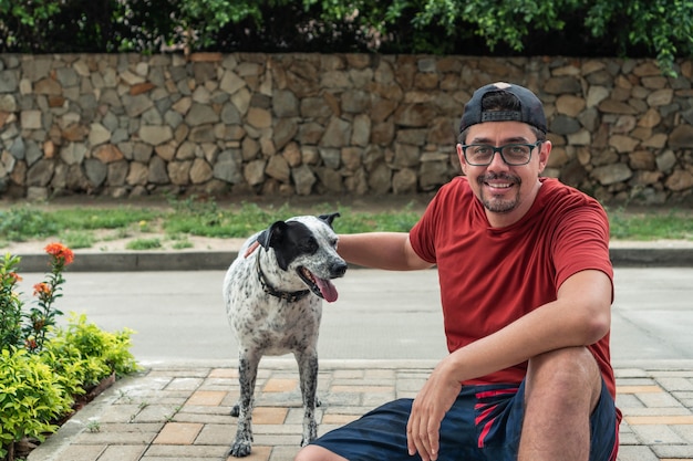 Hombre mayor con perro por la mañana. El hombre lleva una gorra negra.