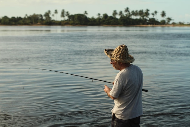 Hombre mayor pescando en el lago durante la puesta del sol