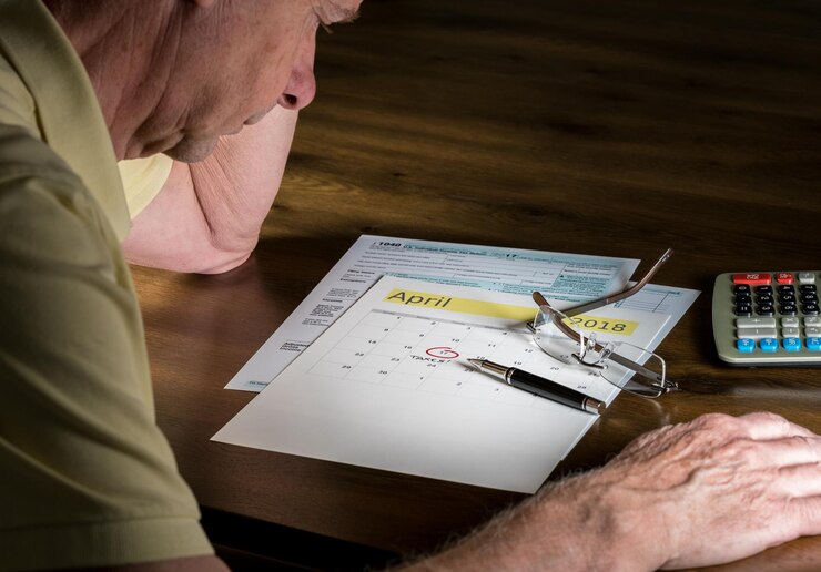 Foto hombre mayor con pluma y calendario en la mesa