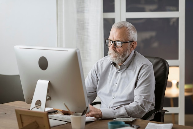 Foto hombre mayor que se conecta con su computadora en casa