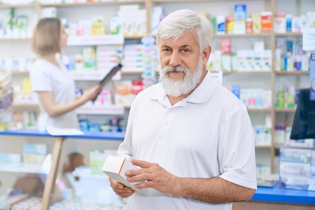 Hombre mayor que elige la medicina en la farmacia