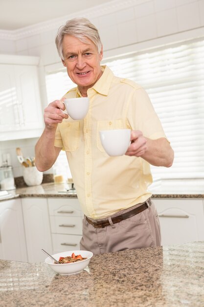 Hombre mayor que ofrece la taza a la cámara