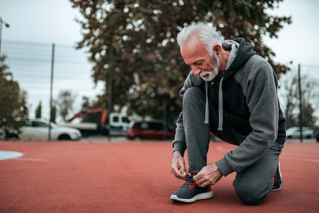 Hombre mayor que se prepara para una corrida en estadio al aire libre.