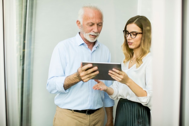 Hombre mayor que presenta datos a la mujer joven en la tableta digital