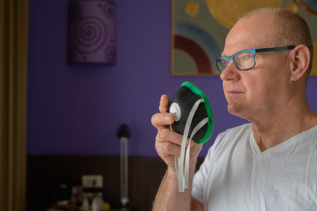 Foto hombre mayor que sostiene la mascarilla para proteger del smog de la contaminación