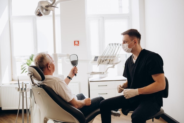 Hombre mayor que tiene tratamiento dental en el consultorio del dentista