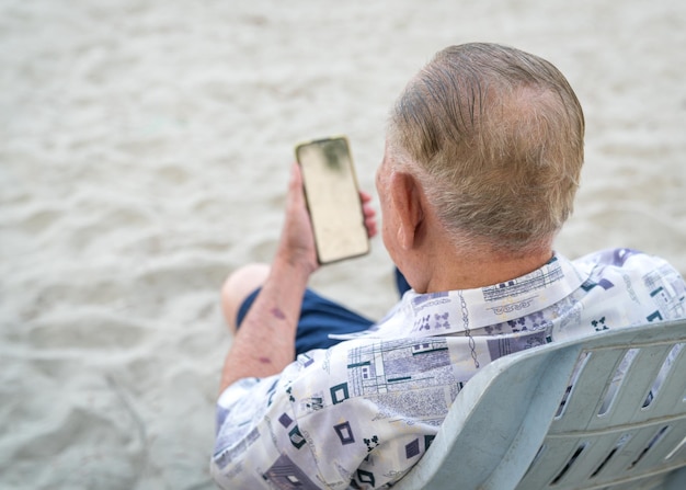 Hombre mayor que usa su teléfono inteligente para leer
