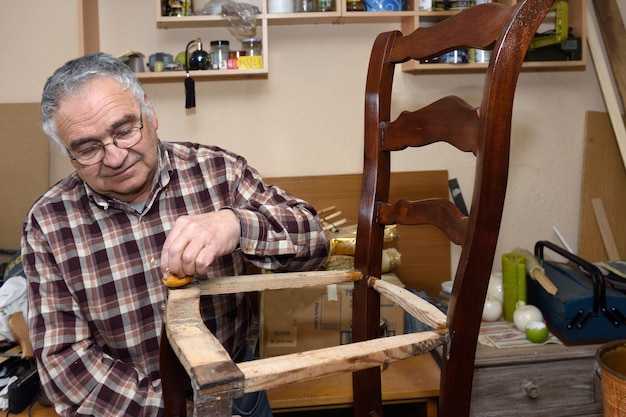 Hombre mayor restaurando una silla